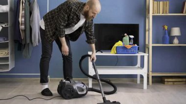 Adam elektrikli süpürge kullanarak evin zeminini süpürüyor. Günlük rutin ve temizlik konsepti. Boşluğu kopyala