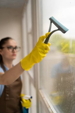 Ofisteki kadın temizleyici özel paspas ve seçici odak kullanarak pencereleri temizliyor