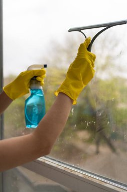 Özel sprey ve temizlik ve dezenfeksiyon için paspas kullanarak kadın elini sarı eldivenle yıka. Temizlik ve ev işi kavramı