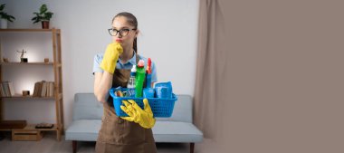 Önlüklü, eldivenli, düşünceli temizlikçi kadın elinde sepetle etrafı temizliyor ve ürünleri dezenfekte ediyor. Pankart. Boşluğu kopyala