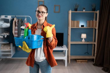 Önlüklü hademe ve temizlik malzemeleriyle dolu sepet tutan eldivenler. Sırt sırta, el ve baş parmak yukarı. Boşluğu kopyala