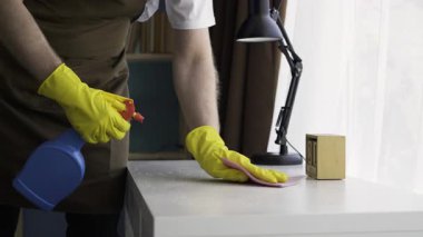 Sakallı adam masaları dezenfektan sprey ve bezle temizliyor. Oda servisi, ev işi ve ev temizliği konsepti