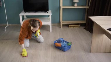 Oda servisi ve temizlik konsepti. Sarı eldivenli uzun saçlı adam evde toz temizleme spreyi kullanıyor. Boşluğu kopyala