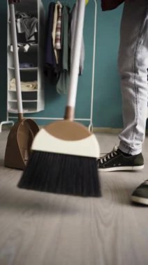 Plastik süpürgeyle yerleri süpüren adama yakın çekim. Temizlik ve ev işi konsepti. Dikey video