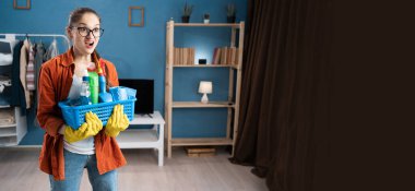 Sinirli ev hanımı, elinde temizlik sepetini tutarak hayal kırıklığını, inançsızlığı ve abartılı duygusal tepkiyi ifade ettiğini söylerken yüzünü buruşturuyor. Pankart. Boşluğu kopyala