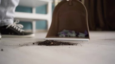 Evdeki faraş ve süpürge kullanarak toprağı ve toprağı süpüren adama yaklaş. Boşluğu kopyala