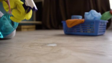 Oda servisi, temizlik ve temizlik konsepti. Sarı eldivenli bir adam evdeki toz toprağını sprey ile temizliyor. Yakın plan.