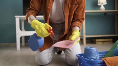 Sarı eldivenli bir adam evdeki bez temizleyicisine deterjan püskürtüyor. Temizlik, ev işi ve temizlik konsepti
