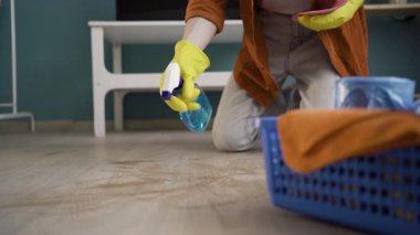 Oda servisi ve temizlik konsepti. Uzun saçlı, eldivenli bir adam evde toz temizleme spreyi kullanıyor. Boşluğu kopyala