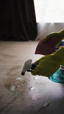 Ev işi, temizlik ve temizlik konsepti. Adamın evdeki toz temizleme spreyi ve bez temizleme zeminini kullanarak tozunu sildiği yakın plan. Dikey video