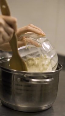Aşama aşama eclair tarifi, şef tencereye un ekler ve hamuru ahşap spatulayla karıştırır, geleneksel Fransız tatlı hazırlığı. Dikey video