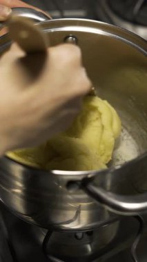 Aşama aşama eclair tarifi, şef choux hamur işini spatulayla karıştırarak geleneksel Fransız tatlısını yapma yöntemini gösteriyor. dikey video