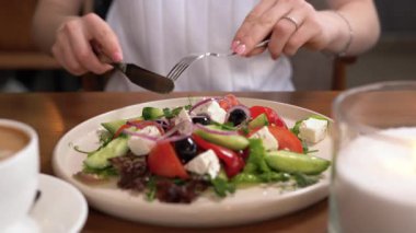 Kahvaltı için restoranda Yunan salatası, sebze ve peynir yiyen bir kadın. Diyetsel beslenme kavramı. Boşluğu kopyala