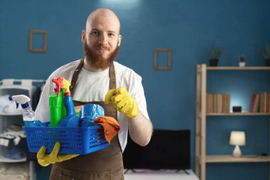 Kapıcı sakallı adam elinde önlükle temizlik malzemeleriyle seni ya da kamerayı işaret ediyor. Temizlik, temizlik ve ev işi konsepti