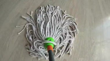 Profesyonel temizlikçi, parlak bir odada yerleri kaplıyor. Islak paspas pürüzsüzce süzülür, kiri siler ve ahşap parıltısını onarır. Rutin ev temizliği için ideal..