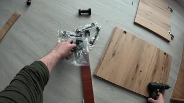 İnsan evdeki matkap ve vidaları kullanarak dolabı kuruyor, yakın plan. Mobilya montaj konsepti. POV.