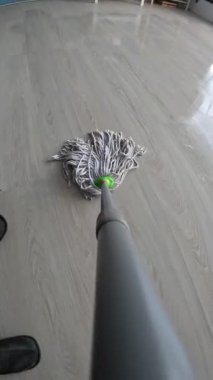 Ev temizliği, temizlik, ev işi ve günlük ev işleri kavramını gösteren, ahşap zemini yukarıdan silen bir adamın görüntüsü.