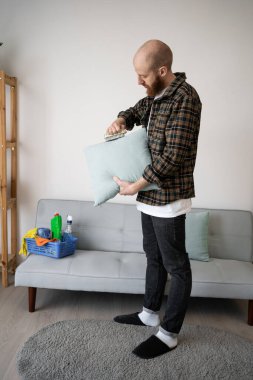 Evde temizlik, ev işleri ve yastık bakımı yaparken yastığı fırçalayan bir adamın yakın çekimi.