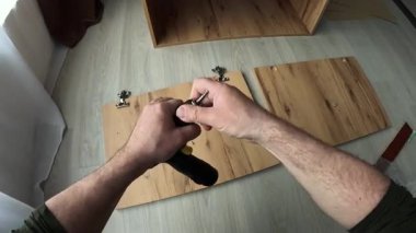POV Man evde kablosuz matkap kullanarak mobilya montajı, matkap ucu değiştirme, DIY görevi sırasında el kapatma, ev geliştirme ve tamirat konsepti