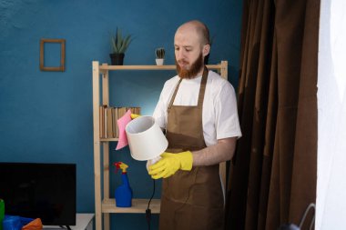 Lambayı toz beziyle silen önlüklü adam. Ev temizliği ve ev işleri konsepti