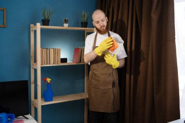 Lambayı toz beziyle silen önlüklü adam. Ev temizliği ve ev işleri konsepti