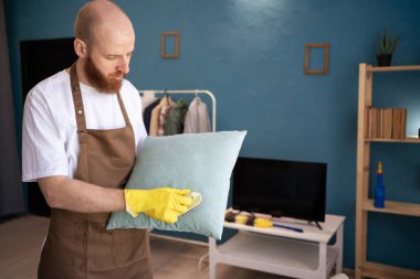 Temizlikçi evde fırçayla yastık temizliyor. Ev işleri, ev işleri ve ev işleri kavramı