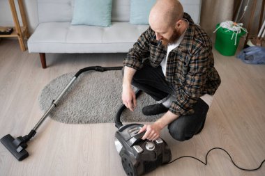 Sakallı, evi temizleyen, elektrikli süpürgenin yanında oturan yakışıklı genç adam süpürmeye başladı. ev işleri