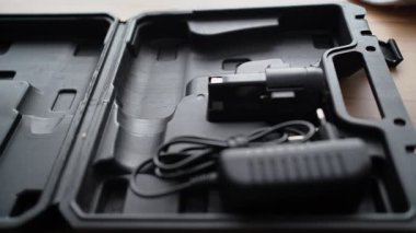 Bir ustanın eli bir kutuya elektrikli matkap koyar ve kapağı kapatır. Yakın plan.