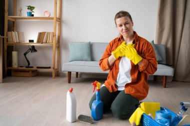 Zihin huzuru kavramı. Minnettar bir ev hanımı göğsünün üstünde oturmuş temizlik malzemeleriyle stres hissetmeden oturuyor. Kameraya bakıyorum.