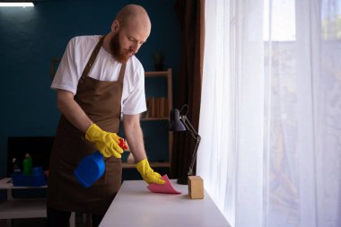 Ev masası yüzeyini dezenfektan spreyiyle temizliyorum. Evde dezenfekte edilen önleme. Boşluğu kopyala