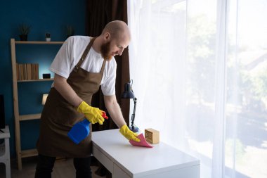 Ev masası yüzeyini dezenfektan spreyiyle temizliyorum. Evde dezenfekte edilen önleme. Boşluğu kopyala