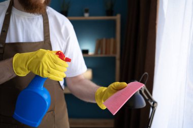 Erkek hademe paçavraya dezenfektan püskürtüyor. Temizleniyor. Yakın plan.