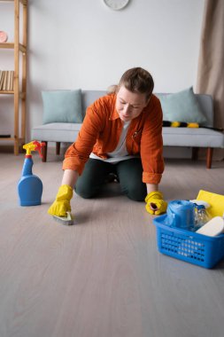 Ev işleri, temizlik ve ev temizliği konsepti. Sarı lastik eldivenli bir kadın fırçayla yerleri fırçalayacak. Boşluğu kopyala