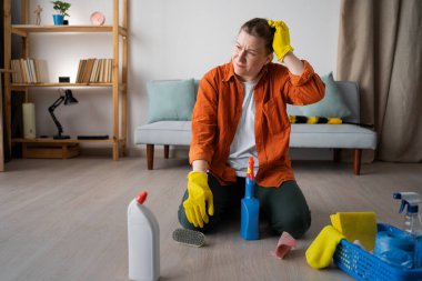 Ev üstüne ev temizliği yapan düşünceli bir kadın. Kafa karıştırma problemi. Ev hanımı dairesini topluyor temizlik malzemeleriyle yerde oturuyor, ev işlerini yapıyor. Boşluğu kopyala