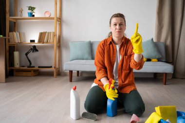 Genç kadın ev temizliği harika bir fikir, ilham bulmak. Ev hanımı dairesini topluyor temizlik malzemeleriyle yerde oturuyor, ev işlerini yapıyor. Boşluğu kopyala