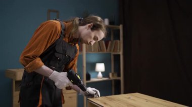 Mobilya montajı için elektrikli matkap kullanan mavi kapaklı tamirci eve dolap kuruyor. Profesyonel marangozluk ve marangozluk kavramı