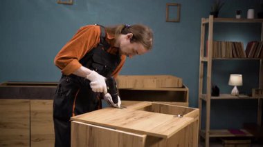 Tamirci mobilya menteşesi takıyor. Mobilyaları monte etmek ve kapı menteşelerini tamir etmek. Boşluğu kopyala