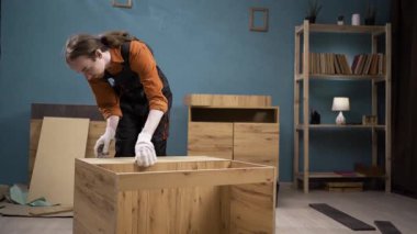 Mavi tulumlu marangoz müşterilerin evinde mobilya monte ediyor. Mobilya montajı ve kurulum kavramı