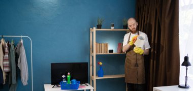 Evdeki temizlik sırasında lambanın tozunu silen adam ev işleri, temizlik, günlük temizlik, sorumlu ev bakımı ve yüzey hijyeni bakımı kavramını gösteriyor.