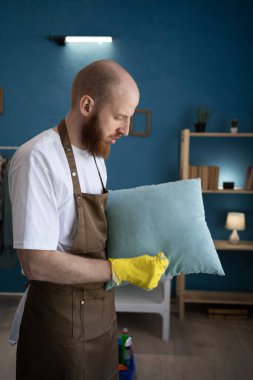 Profesyonel temizlik servisinden erkek hademe ev içi fırçayla yastık fırçalıyor. Ev işleri, ev işleri ve temizlik konsepti. Boşluğu kopyala