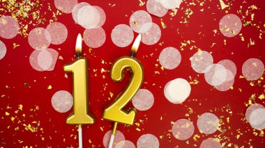Altın yanan mum numarası 12. Kırmızı arka planda 12 yazılı doğum günü tebrik kartı konfeti ve simle. Yıldönümü, kutlama etkinliği ve doğum günü konsepti.