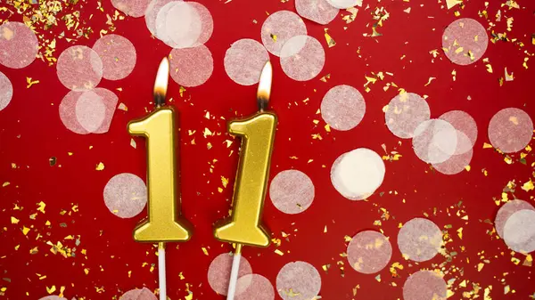 Altın yanan mum numarası 11. Kırmızı arka planda 11 yazısıyla birlikte konfeti ve simle doğum günü tebrik kartı. Yıldönümü, kutlama etkinliği ve doğum günü konsepti.