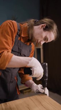 Mobilya montajı için elektrikli matkap kullanan mavi kapaklı tamirci eve dolap kuruyor. Profesyonel marangozluk ve marangozluk kavramı