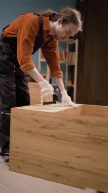 Üretim ve üretim konsepti. Zımba tabancasıyla mobilya montajlayan genç bir derleyici. Boşluğu kopyala