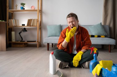 Birden fazla iş yapan ev hanımı temizlik malzemeleriyle yerde oturuyor. Oda servisi, ev işi, ev ve ev temizliği konsepti