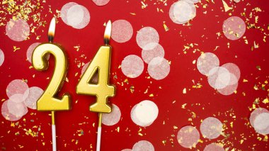 Altın yanan mum numarası 24 numara. Kırmızı arkaplanda 24 yazılı doğum günü tebrik kartı konfeti ve simle. Yıldönümü, kutlama etkinliği ve doğum günü konsepti.