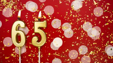 Altın yanan mum numarası altmış beş. Kırmızı arkaplanda 65 yazılı doğum günü tebrik kartı konfeti ve simle. Yıldönümü, kutlama etkinliği ve doğum günü konsepti.