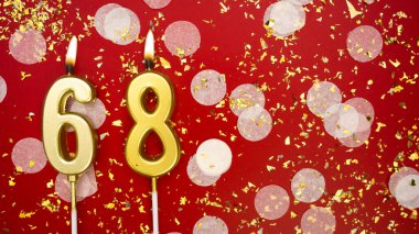 Altın yanan mum numarası 68 'di. Kırmızı arkaplanda 68 yazılı doğum günü tebrik kartı konfeti ve simle. Yıldönümü, kutlama etkinliği ve doğum günü konsepti.