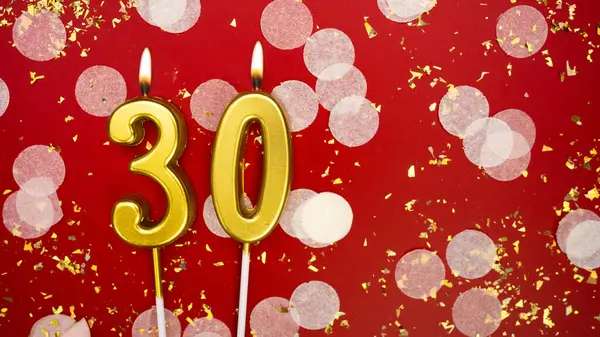 Altın yanan mum numarası 30. Kırmızı arkaplanda 30 yazılı doğum günü tebrik kartı konfeti ve simle. Yıldönümü, kutlama etkinliği ve doğum günü konsepti.