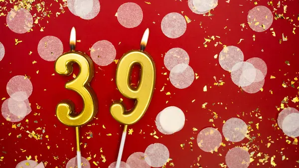 Altın yanan mum numarası 39 numara. Kırmızı arka planda 39 yazısıyla birlikte konfeti ve simle birlikte doğum günü tebrik kartı. Yıldönümü, kutlama etkinliği ve doğum günü konsepti.